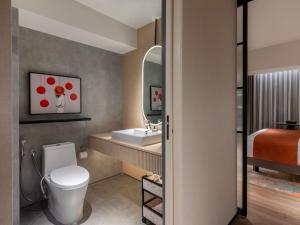 a bathroom with a toilet and a sink and a bed at Herloom Hotel & Residence BSD Tangerang in Tangerang