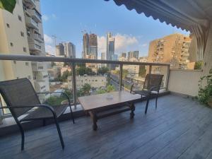 a balcony with a table and chairs and a view of a city at Renovated central 4 bedroom apt with great terrace and Bomb Shelter in Ramat Gan
