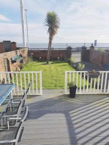 a deck with a white fence and a palm tree at Roker North cliff Sea View in Sunderland