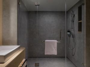 a bathroom with a shower and a white towel at Herloom Hotel & Residence BSD Tangerang in Tangerang