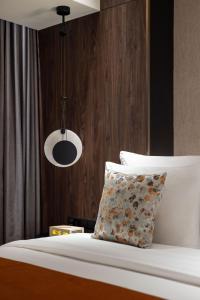 a bed with a pillow and a pendant light at Herloom Hotel & Residence BSD Tangerang in Tangerang