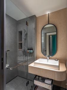 a bathroom with a sink and a mirror at Herloom Hotel & Residence BSD Tangerang in Tangerang