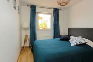 een slaapkamer met een bed met blauwe gordijnen en een raam bij Le Balmoral - Plage à 1 min - ménage inclus - terrasse lumineuse in Wimereux