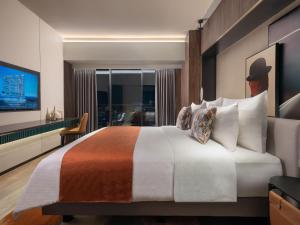 a hotel room with a large bed and a window at Herloom Hotel & Residence BSD Tangerang in Tangerang