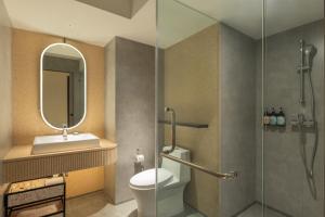 a bathroom with a toilet and a sink and a mirror at Herloom Hotel & Residence BSD Tangerang in Tangerang