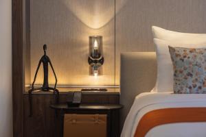 a hotel room with a bed and a night stand with a phone at Herloom Hotel & Residence BSD Tangerang in Tangerang