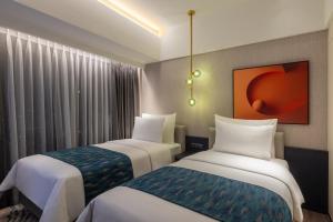 a hotel room with two beds and a painting on the wall at Herloom Hotel & Residence BSD Tangerang in Tangerang
