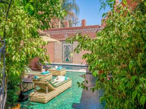 a courtyard with chairs and a pool with trees at Riad Dar Sido in Marrakech