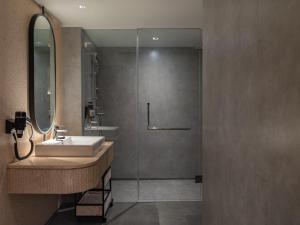 a bathroom with a sink and a glass shower at Herloom Hotel & Residence BSD Tangerang in Tangerang