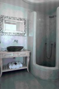 a bathroom with a sink and a shower with a mirror at El Greco Resort & Spa in Fira