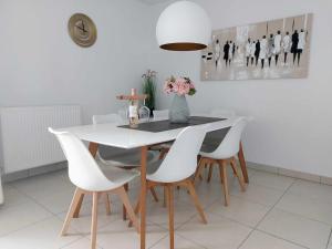 a dining room with a white table and white chairs at Duplex Villa Capricia appartement met zwembad Nieuwpoort Jachthaven in Nieuwpoort