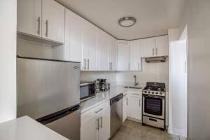 a white kitchen with white cabinets and a refrigerator at Midtown East 2br w elevator nr train NYC-1255 in New York