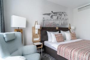 a bedroom with a bed and a blue chair and a chair at Hotel Aquarion Family & Friends - Destigo Hotels in Zakopane