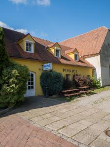 un edificio amarillo con un banco de picnic delante de él en Hotel Club, en Vranovská Ves