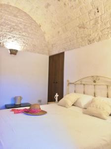 sypialnia z białym łóżkiem i kamienną ścianą w obiekcie Trulli Bosco Selva w Alberobello