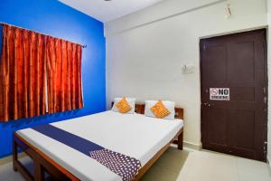a bedroom with a bed with a blue wall and a door at SPOT ON S.k Guest House in Calangute