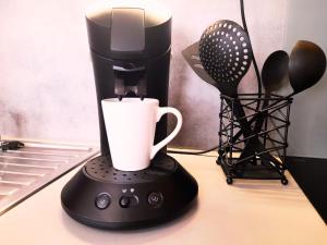 - une cafetière noire avec une tasse sur un comptoir dans l'établissement Le Cocon Beauvaisien - Hyper Centre - Wifi Fibre - TV HD, à Beauvais
