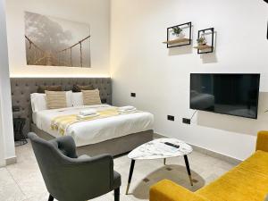 een slaapkamer met een bed en een tv en een bank bij Tennessee Urban Suites in Málaga