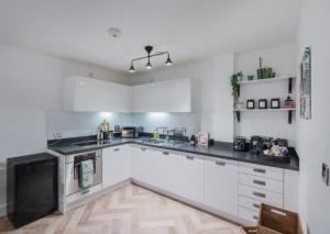 a kitchen with white cabinets and black counter tops at Mailbox 2 bed Apartment Birmingham City Centre - Free Parking in Birmingham