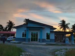a small blue house with a palm tree in the background at NAYLA Homestay Perlis in Simpang Empat