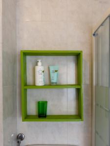 a green shelf with two bottles and a green cup in a bathroom at Host4All casa vacanze in Falconara Marittima