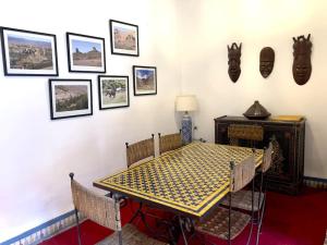 a dining room with a table and some pictures on the wall at Riad Amethyste in Marrakesh