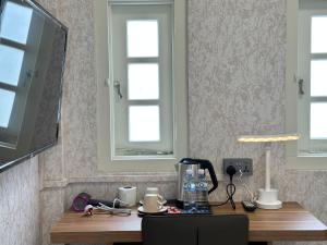 einen Schreibtisch in einem Zimmer mit 2 Fenstern und einem TV in der Unterkunft Kam Leng Hotel in Singapur