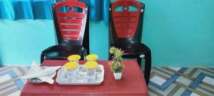 uma mesa vermelha com duas cadeiras e um prato de comida em Poddar Retreat Managed by Wheels And Wings em Dām Dim