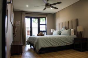 a bedroom with a large bed with a ceiling fan at Annexure A - Lovely brand new 2 bedroom flat in Groenkloof in Pretoria