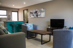 a living room with a couch and a table and a tv at Annexure A - Lovely brand new 2 bedroom flat in Groenkloof in Pretoria
