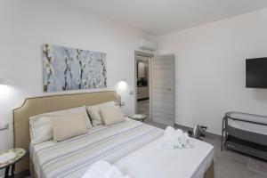 a bedroom with a bed with white sheets and a tv at Garden House in Pianillo