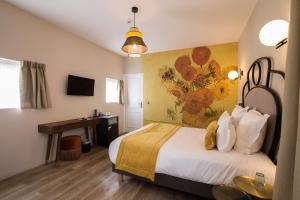 a bedroom with a bed and a desk in a room at Hotel des Iris in Auvers-sur-Oise