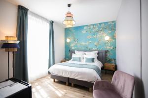 1 dormitorio con cama y pared azul en Hotel des Iris en Auvers-sur-Oise