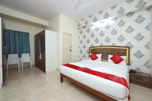 班加罗尔Hotel Amulya Relax Inn的卧室里有一张白色的大床，上面有红色的枕头