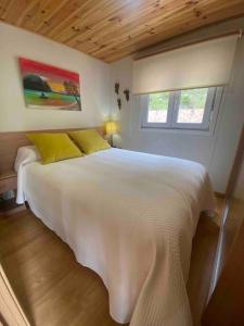 1 cama blanca con 2 almohadas amarillas en un dormitorio en Le petit paradis, en Hío