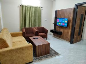 a living room with two chairs and a tv at Hotel Bulande Comforts-1 Bedroom Flat in Bangalore