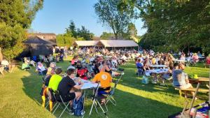 a crowd of people sitting at tables in the grass at Silvestone Farm Campsite in Silverstone