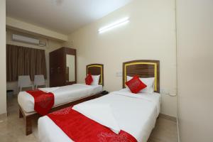 班加罗尔Hotel Amulya Relax Inn的两张位于酒店客房的床铺,配有红色枕头