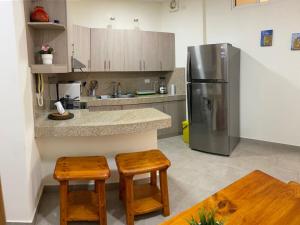 a kitchen with a stainless steel refrigerator and wooden stools at GARZOTA SUITE DEL ARTE 3er Piso in Guayaquil