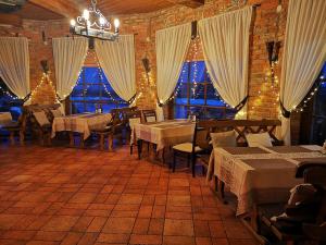 un restaurante con mesas, sillas y ventanas en Meškių dvarkiemis, en Bubiai
