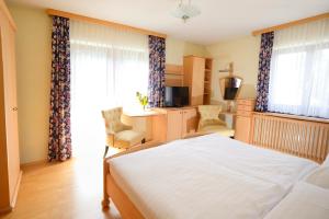 a bedroom with a large white bed and a desk at Hotel Mönichwalderhof in Mönichwald +68 photos