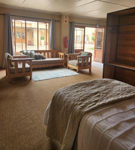 a bedroom with a bed and two chairs and a couch at Casa Mia Health Spa and Guesthouse in Addo