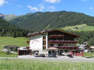 un gran edificio con coches estacionados en un estacionamiento en Aparthotel Garni Monte, en Kartitsch