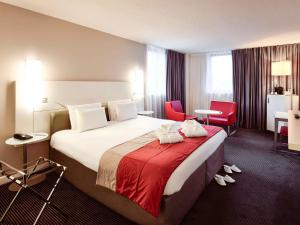Cette chambre d'hôtel comprend un grand lit et des chaises rouges. dans l'établissement Mercure Lyon Centre Saxe Lafayette, à Lyon