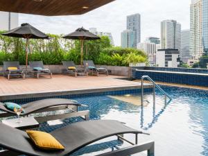 a swimming pool with chairs and umbrellas on a building at Pullman Bangkok Hotel G in Bangkok