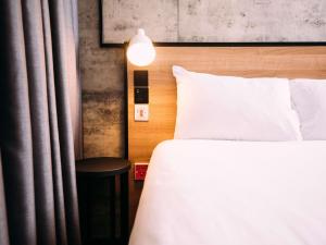 ein Schlafzimmer mit einem weißen Bett und einer Lampe in der Unterkunft ibis Belfast City Centre in Belfast