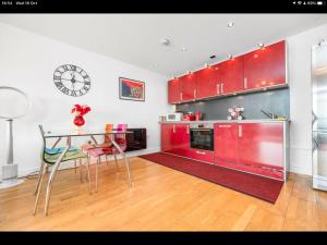 uma cozinha com armários vermelhos, uma mesa e um relógio em Stunning Spacious City Apartment with free parking em Cardiff
