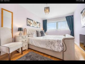 1 dormitorio con cama, silla y espejo en Stunning Spacious City Apartment with free parking, en Cardiff