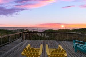 a deck with two chairs and a sunset at Comfort Inn on the Ocean in Kill Devil Hills