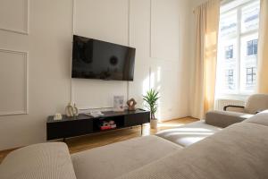 Vibrant 107 m2 flat in the city center في فيينا: غرفة معيشة مع كنبتين وتلفزيون بشاشة مسطحة